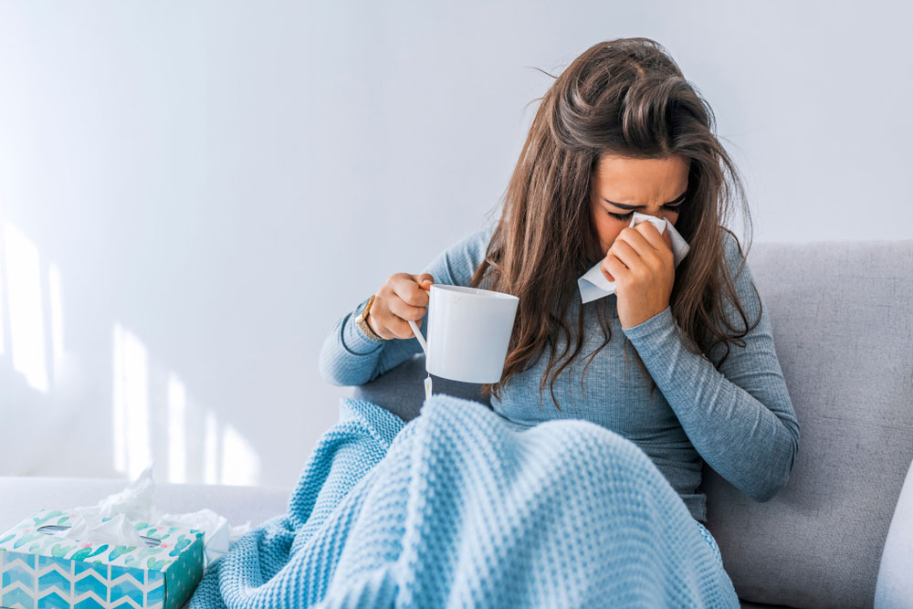woman feeling sick on the couch drinking tea