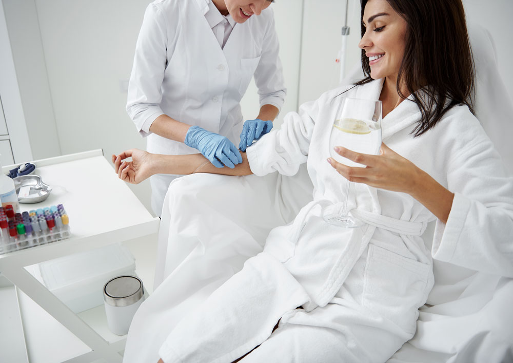 woman receiving iv hydration therapy while drinking lemon water